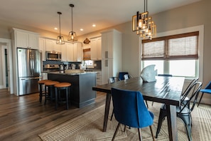 Prepare meals and socialize in this kitchen with a central island, bar stools, stainless steel appliances, and a large dining table.