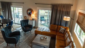 Ein geräumiges Wohnzimmer mit einem großen braunen Ledersofa, zwei Sesseln, einem Couchtisch und einem Deckenventilator.