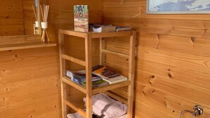 A wooden interior with a shelf holding magazines, a map, and a towel dispenser. - Tepee at the Lama- & Alpakahof Triesenberg (Triesenberg)