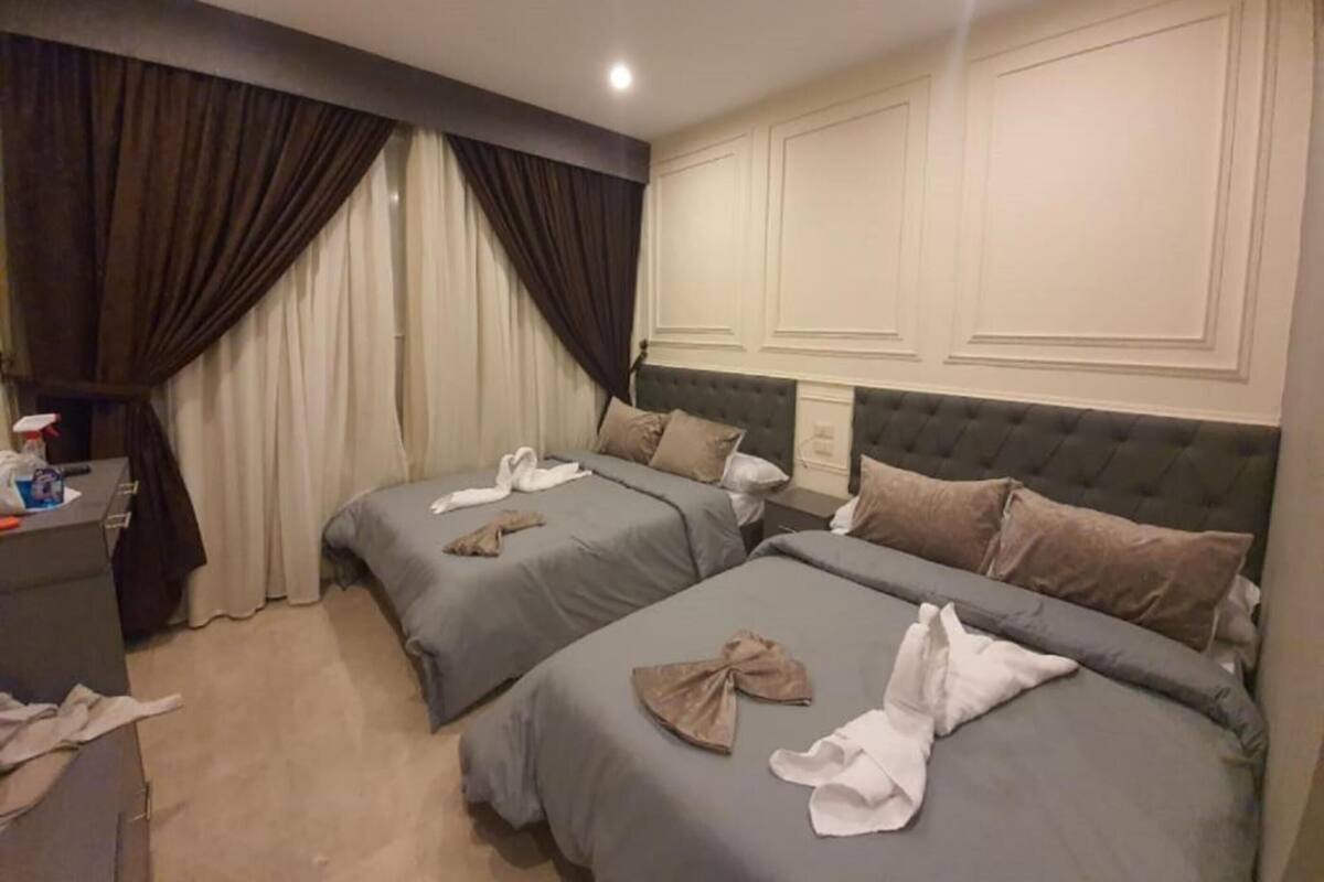 A hotel room with two beds, a desk, and a minibar.