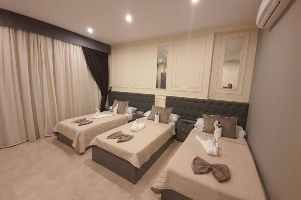 A hotel room with two beds, each with a duvet and pillows, a large mirror, and an air conditioning unit.