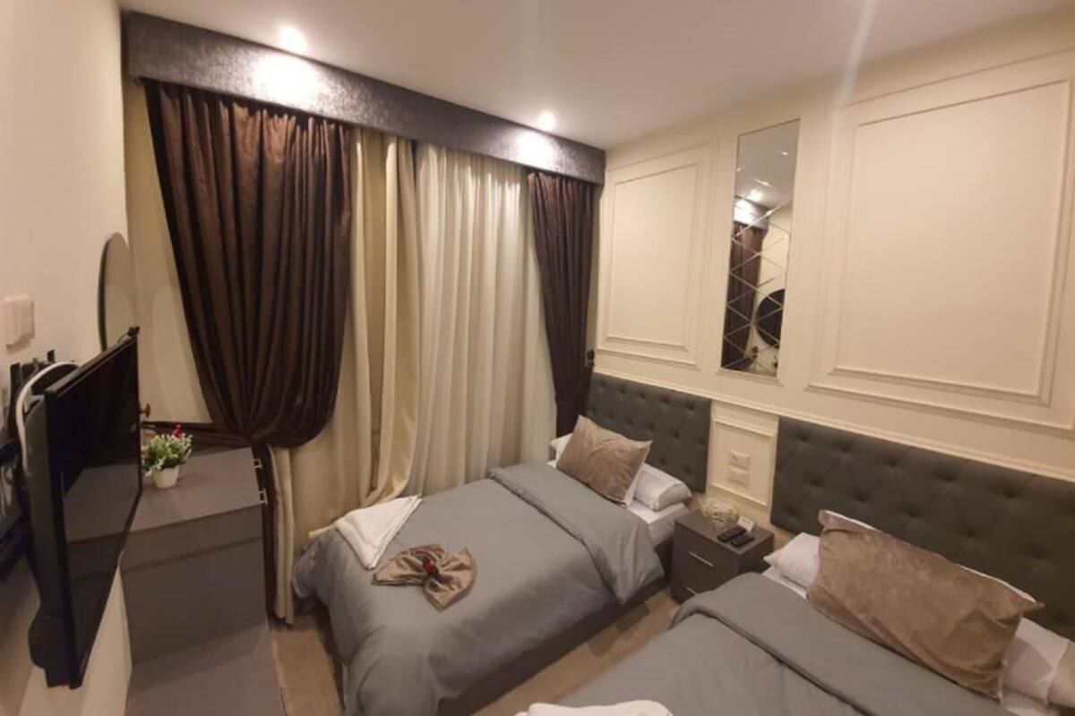 A hotel room with two beds, a large mirror, and a window with curtains.