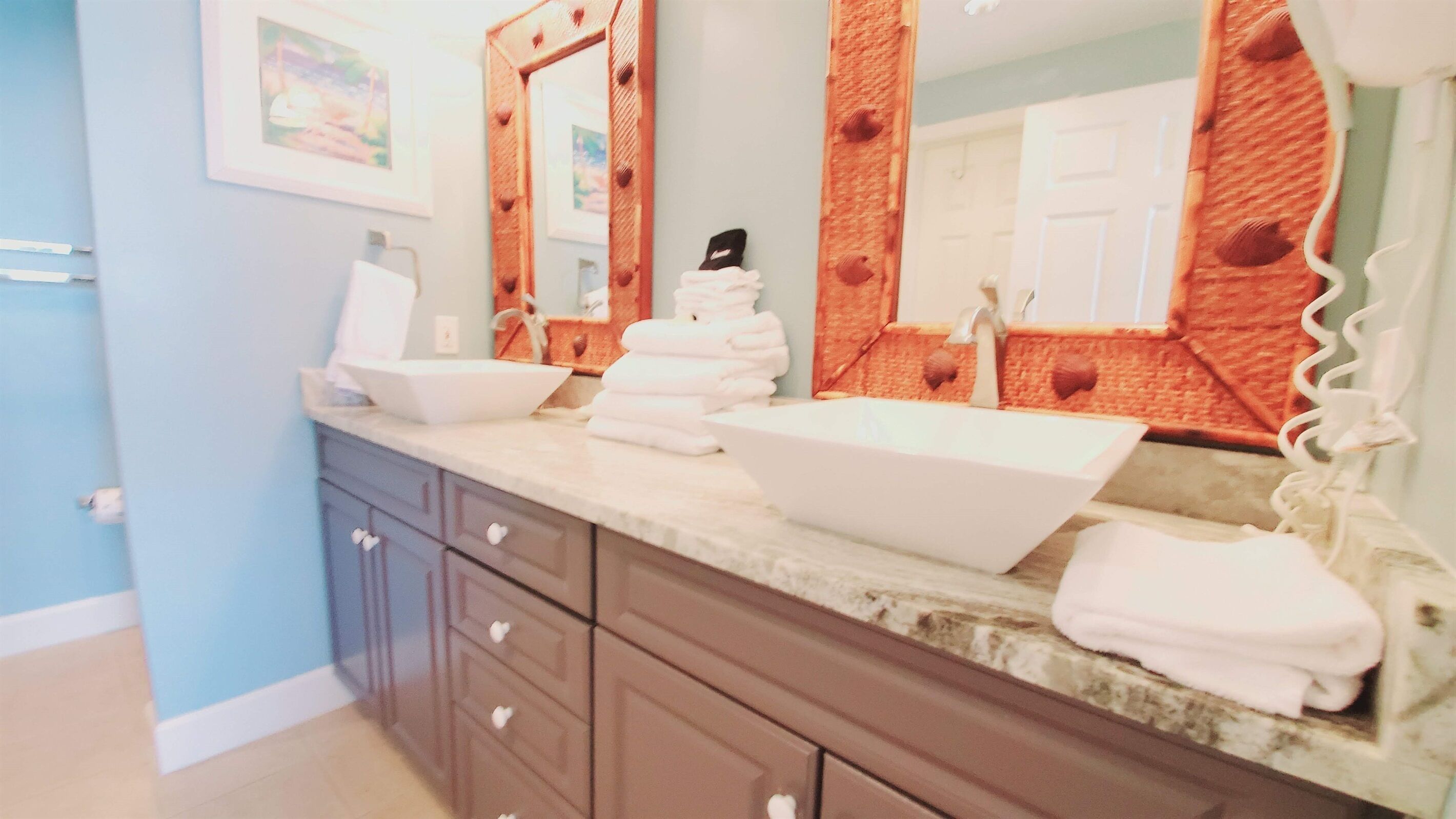 A bathroom with a vanity, two sinks, a mirror, and a towel rack.