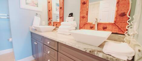 A bathroom with a vanity, two sinks, a mirror, and a towel rack.