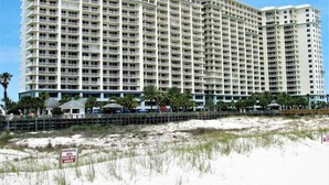 Un hotel grande y de varios pisos con balcones, situado cerca de una playa con un letrero que indica una zona protegida.
