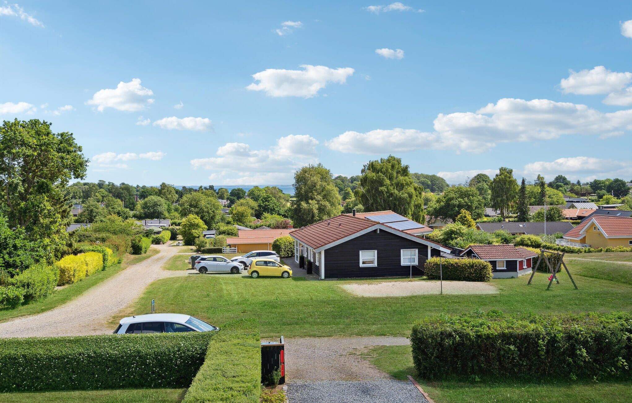 Un quartier résidentiel avec des maisons, une allée gravillonnée et des voitures garées.