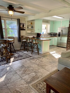 A kitchen with a central island, bar stools, a ceiling fan, and a refrigerator.