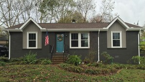 Een huis met twee verdiepingen, een veranda, een blauwe deur en een Amerikaanse vlag.