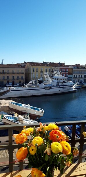 A marina with boats docked, a building with balconies, and a bouquet of flowers in the foreground.