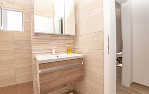 Ein modernes Badezimmer mit einem weißen Waschbecken, einem Spiegel und Holzvertäfelung an den Wänden.