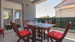 Ein Balkon mit Tisch und Stühlen, eine Schiebetür und Blick auf Gebäude und Grünflächen.
