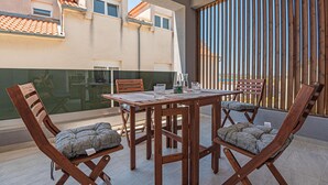 Una mesa de madera con sillas y un separador de vidrio en un balcón.