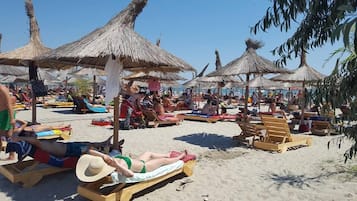 En privat strand, hvidt sand, liggestole, parasoller