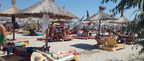 Een privéstrand, wit zand, ligstoelen aan het strand, parasols