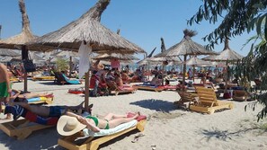 Perto da praia, areia branca, espreguiçadeiras, guarda-sóis 