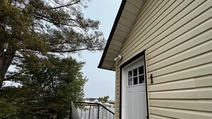 Een huis met een witte deur, een klein terras en uitzicht op een meer.