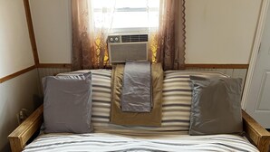 A wooden bed with striped bedding and a central pillow. - Dock Life Beach 1 - Cottage 3, Riverside 2 bedroom, 3 min walk to Beach 1 (Wasaga Beach)