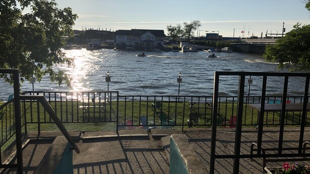 A riverside walkway with a metal railing, benches, and a grassy area. - Dock Life Beach 1 - Cottage 3, Riverside 2 bedroom, 3 min walk to Beach 1 (Wasaga Beach)