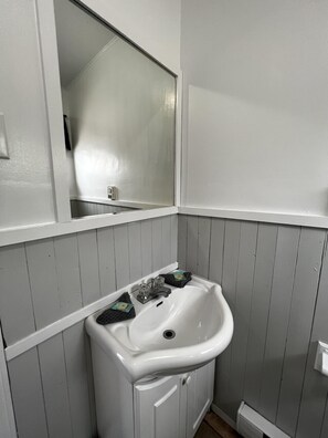 A bathroom with a white sink, a mirror above it, and a towel rack. - Dock Life Beach 1 - Cottage 4, Riverside 2 bedroom, 3 min walk to Beach 1 (Wasaga Beach)