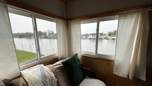 Ein Zimmer mit einem Bett, Blick auf einen See und einer Bootsanlegestelle.