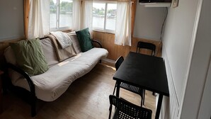 Ein Zimmer mit Holzbalkendecke, einer Couch, einem Tisch und einem an der Wand montierten Fernseher.