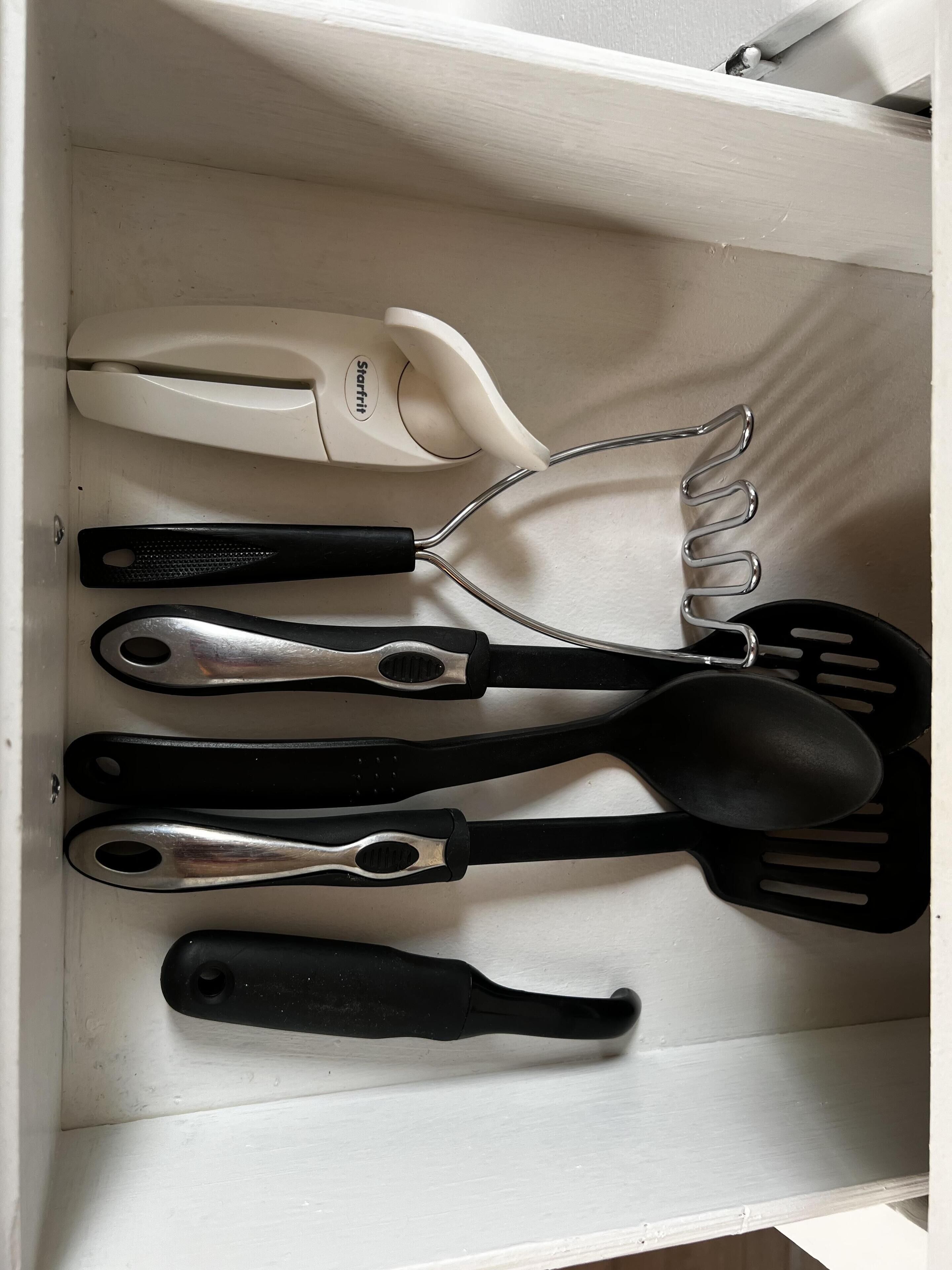 Un cajón con distintos utensilios de cocina, como una espátula, una cuchara y un rallador.