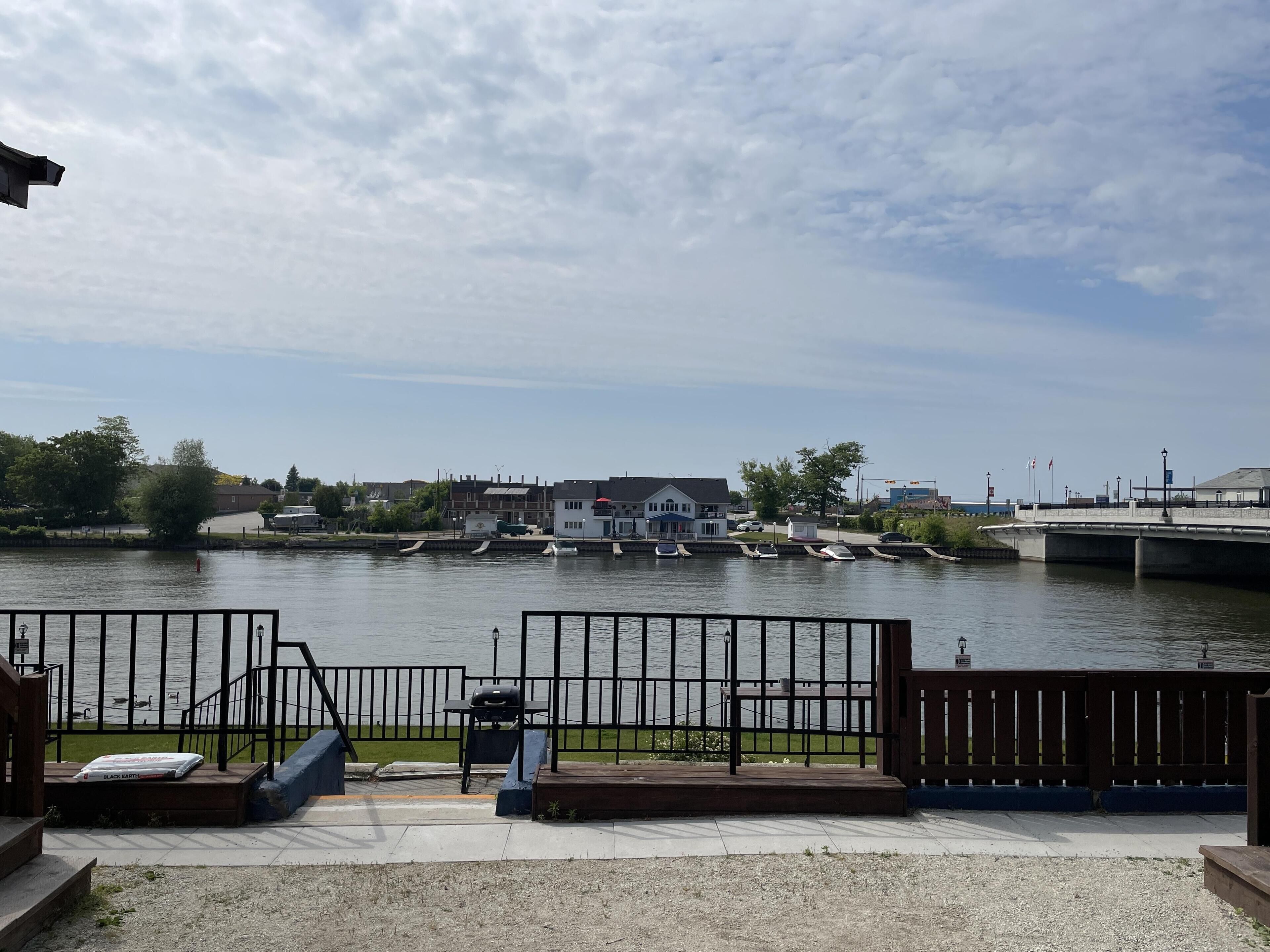 Vista sul fiume con un molo, un ponte e degli edifici sullo sfondo.