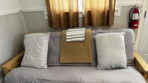 A wooden sofa with grey cushions and a folded blanket. - Dock Life Beach 1 - Cottage 5, Riverside Property, 2 Bdrm, 3 min walk to Beach 1 (Wasaga Beach)