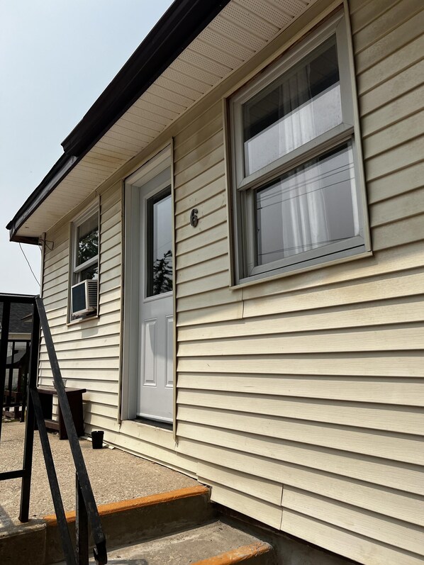 A single-story house with a front door, two windows, and a small porch. - Dock Life Beach 1 - Cottage 6, Riverside Property, 2 Bdrm, 3 min walk to Beach 1 (Wasaga Beach)