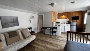 Un ambiente compatto con angolo cottura, divano, tavolo da pranzo e piccola zona cucina.