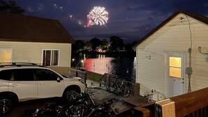Una casa con un molo che si protende sull'acqua, un'auto bianca parcheggiata di fronte e una bicicletta appoggiata alla casa.