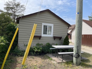 A house with a window, a picnic table, and a utility pole.