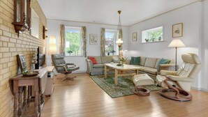 A cozy living room with a brick wall, a wooden floor, a sofa, a coffee table, and a fireplace.