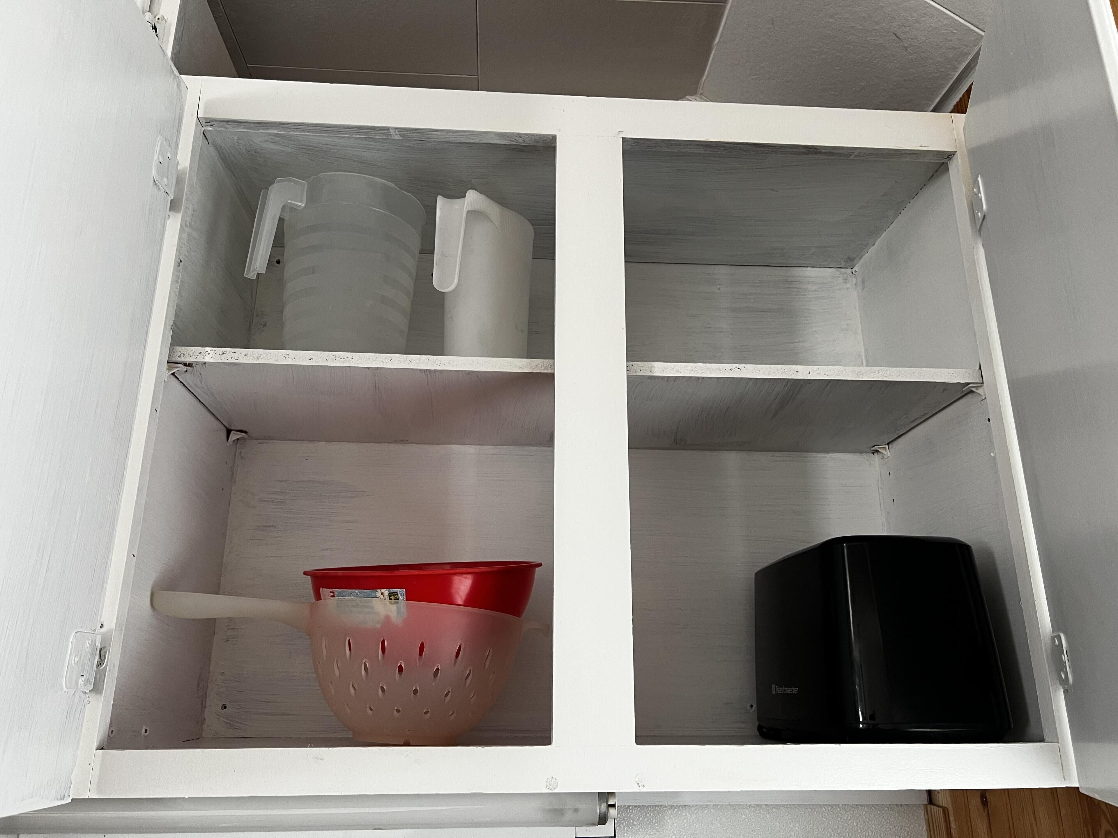 A white cabinet with three shelves, each containing different items.