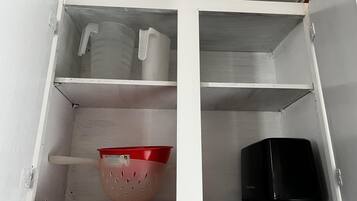 A white cabinet with three shelves, each containing different items.
