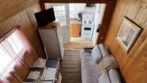 Ett kompakt rum med träpanel på väggarna, utrustat med en säng, ett litet pentry och en matplats.