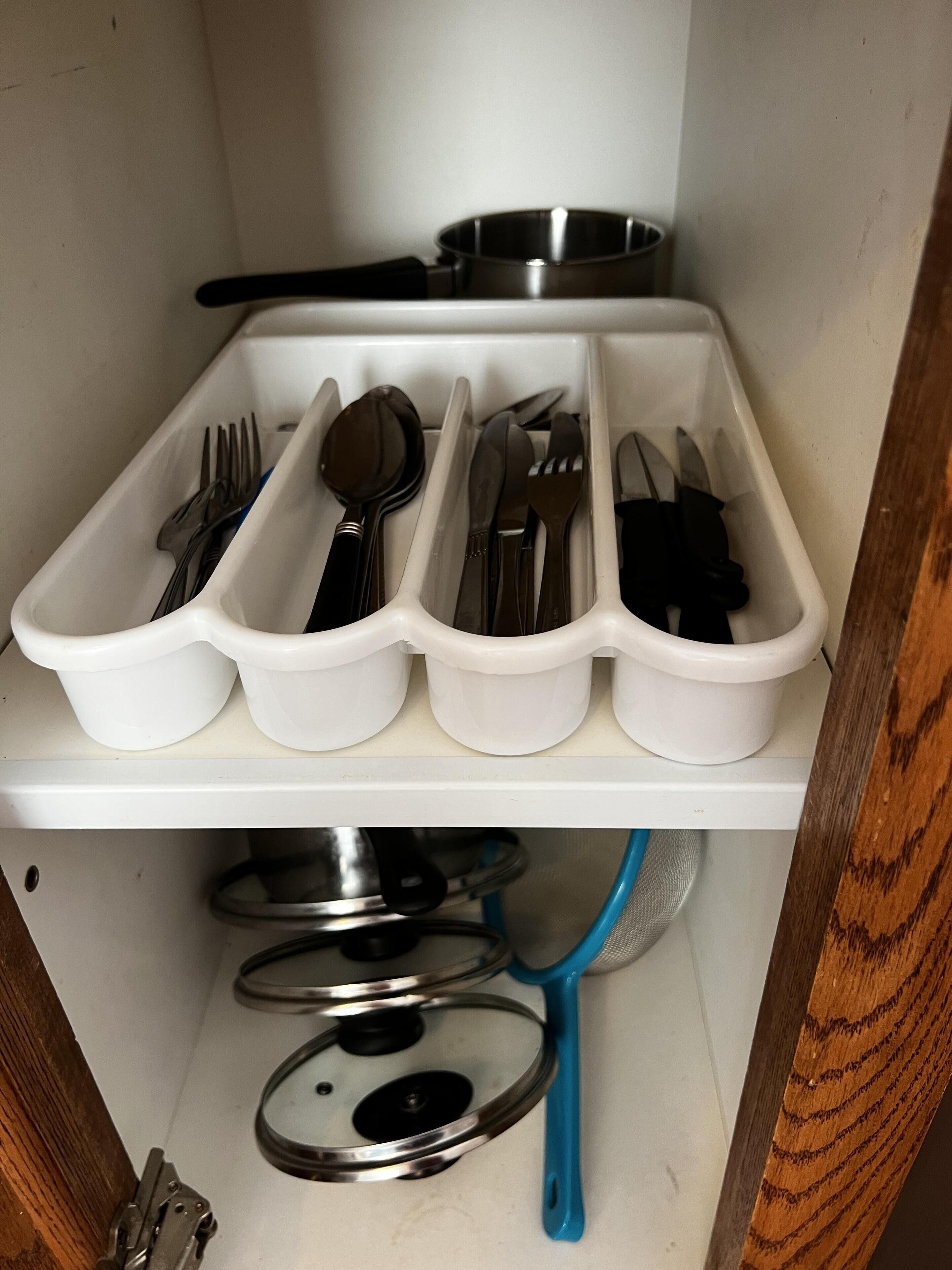A kitchen with white storage containers holding utensils.