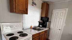 Una cocina compacta con armarios de madera, una estufa blanca y un microondas negro.