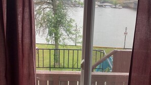 Vista a través de una ventana con cortinas, que muestra un río, un árbol y un puente.