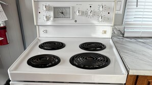 Una estufa blanca con cuatro quemadores y un panel de control con diferentes ajustes.