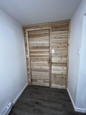 A room with a wooden wardrobe and a dark wooden floor.