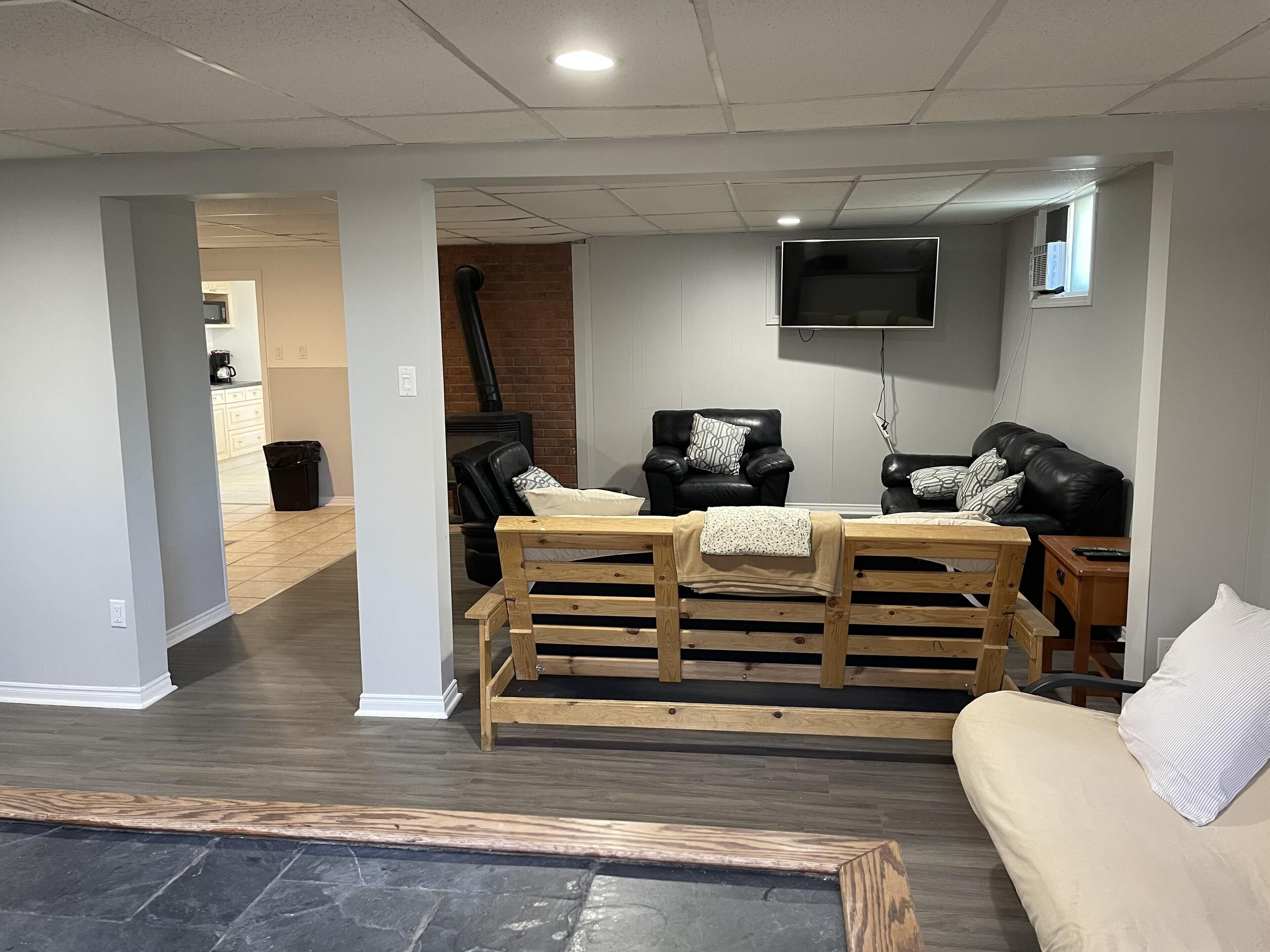 A living room with a fireplace, two black leather sofas, a wooden bench, and a TV mounted on the wall.