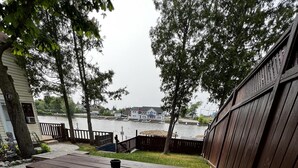 Une table de pique-nique avec un banc, entourée d’une clôture en bois, d’où l’on peut admirer un plan d’eau et des bâtiments en arrière-plan.
