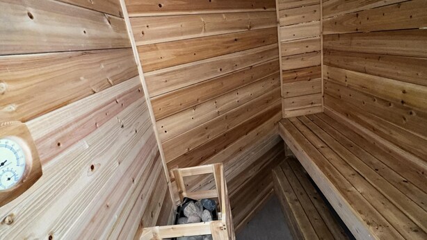 L’intérieur d’une cabane en bois, avec un plafond en pente, une échelle en bois et une horloge au mur.
