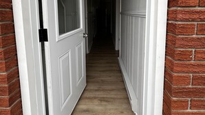 A narrow hallway with white doors and brick walls, leading to a dark interior. - Dock Life Beach 1 - Unit 16, Riverside Property, 2 Bdrm, 3 min walk to Beach 1 (Wasaga Beach)