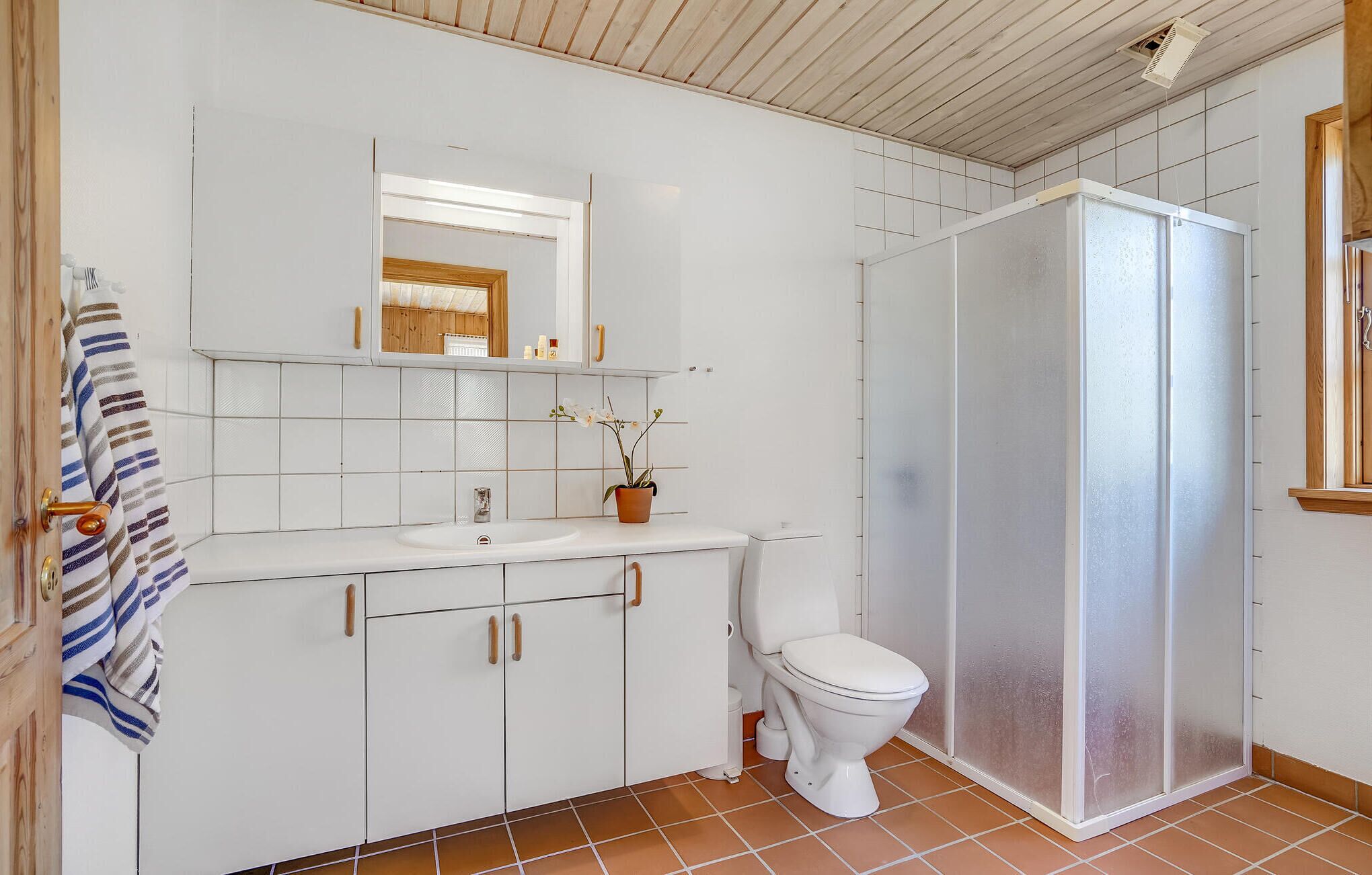 Een badkamer met een wit wastafel, een toilet, een douchecabine en een spiegel boven het wastafel.