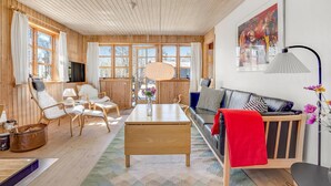Ein gemütliches Wohnzimmer mit Holzwänden, einer Couch, einem Couchtisch und einem Fernseher.