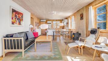 Un salon moderne avec un plafond en bois, un canapé en cuir noir, une table à manger et une cheminée.
