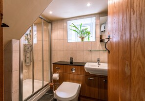 Ein modernes Badezimmer mit Duschkabine aus Glas, einem Holzausleger mit Waschbecken und Toilette.