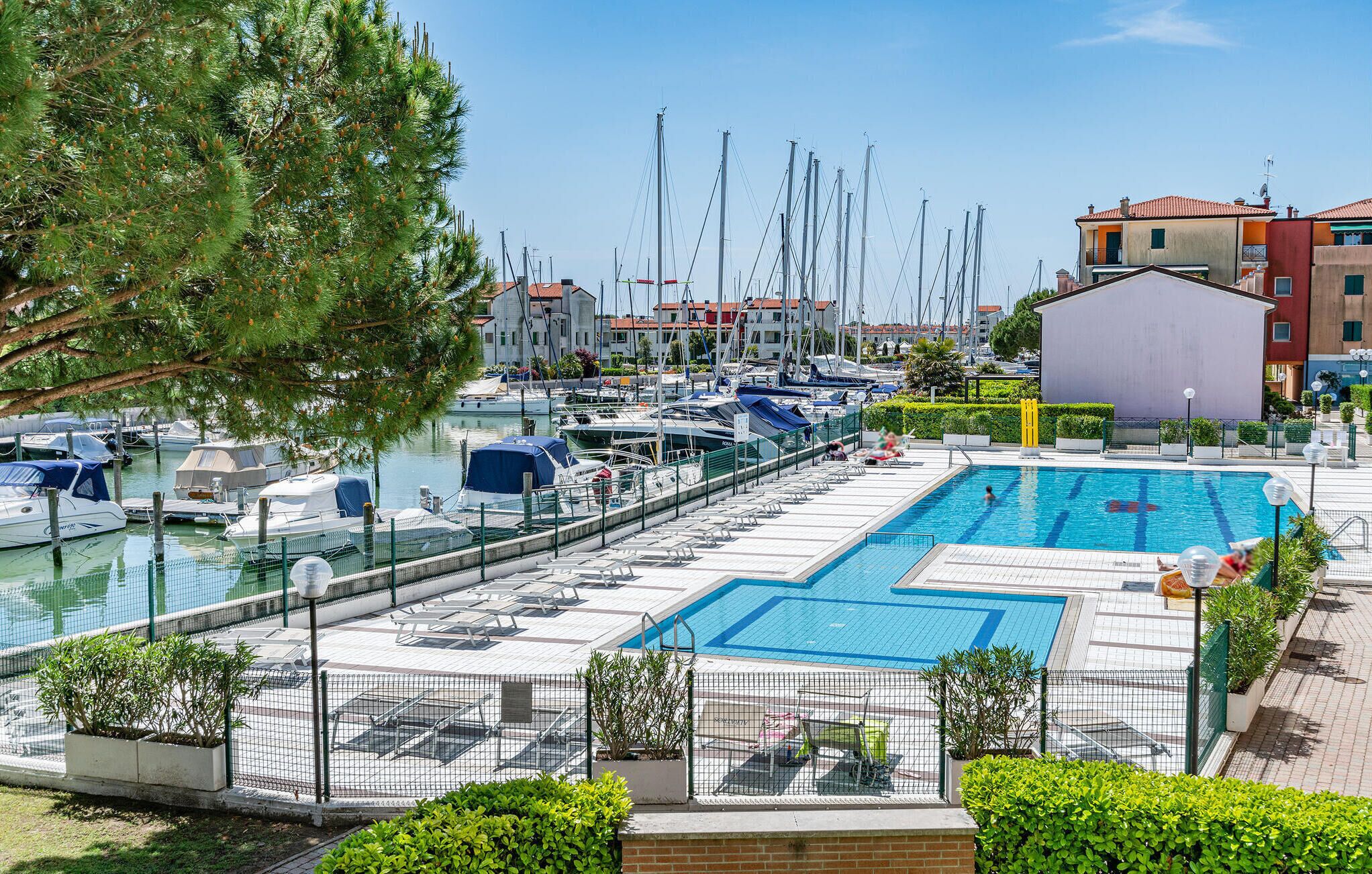 A marina with boats docked, a swimming pool, and surrounding buildings.